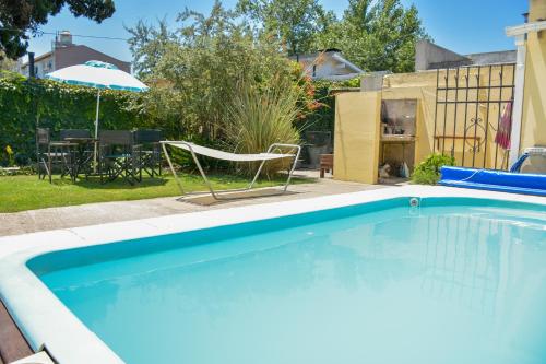 a swimming pool with a chair and an umbrella at Casa con jardín y pileta en Chascomús, cerca de la Laguna in Chascomús