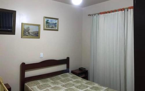 a bedroom with a bed and a curtain and a window at Casa espaçosa a 300m do mar in Piçarras