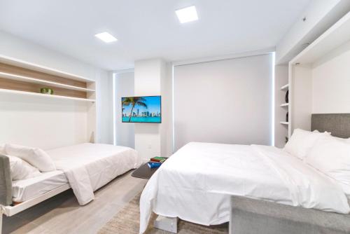 a white bedroom with two beds and a window at Great Miami Stay Steps from Bayside & the Beach in Miami