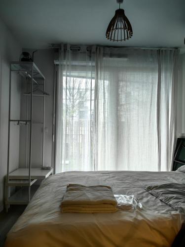 un lit dans une chambre avec une grande fenêtre dans l'établissement Chambre 2Mins Métro, Paris - Disney, Université, à Noisy-le-Grand