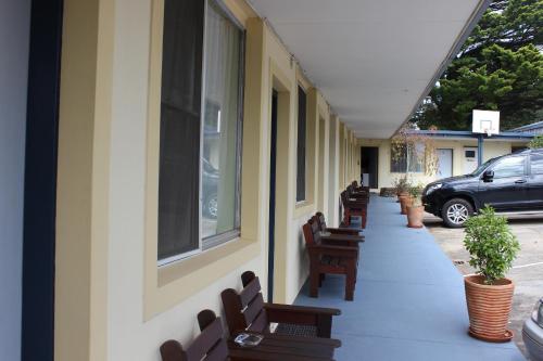 a row of benches on a sidewalk next to a building at High Mountains Motor Inn in Blackheath