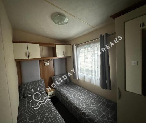 a small room with a bed and a window at Goldfinch - Spacious 2 bed at Seal Bay in Selsey