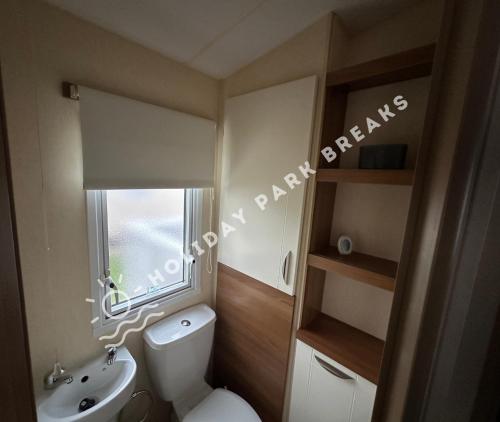 a bathroom with a toilet and a sink and a window at Goldfinch - Spacious 2 bed at Seal Bay in Selsey