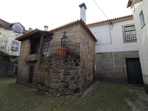 an old stone building with a balcony on the side of it at Casa dos Livros - Guest House in Vila Nova de Tazem