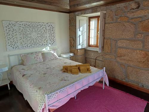 a bedroom with a pink bed and a brick wall at Casa dos Livros - Guest House in Vila Nova de Tazem