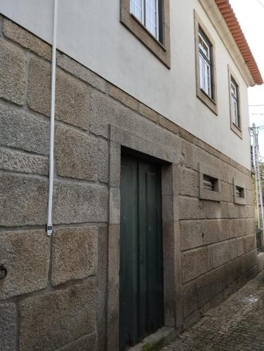 a building with a green door on the side of it at Casa dos Livros - Guest House in Vila Nova de Tazem