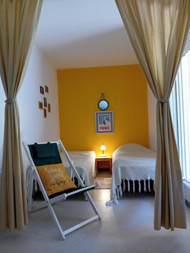 Una habitación con dos camas y una silla y una ventana. en Sur le GR10 et autres sentiers à Aulus-les-Bains, en Aulus-les-Bains