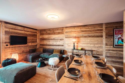 - un salon avec des murs en bois et une table avec des chaises dans l'établissement Appartement Boréal - At the summit of Combloux, à Combloux