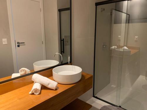 a bathroom with a sink and a glass shower at Cobertura pôr-do-sól com jacuzzi in Bombinhas