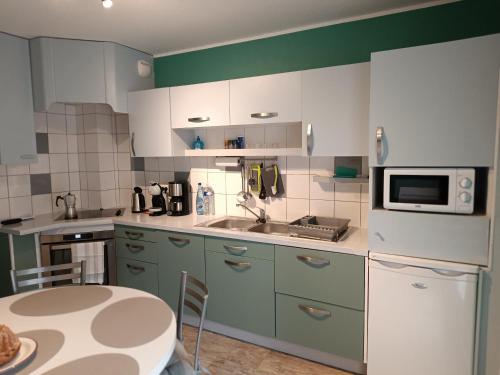 une cuisine avec des placards verts et blancs et une table dans l'établissement LE 46A, à Colmar