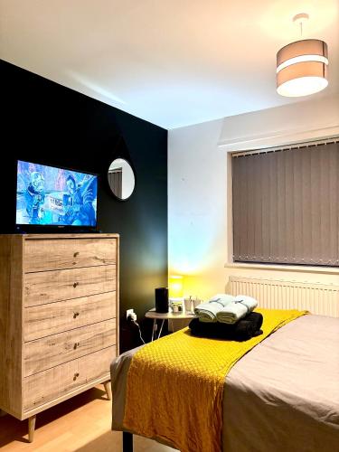 a bedroom with a bed and a dresser with a flat screen tv at CityZen - serviced accomodation in Birmingham