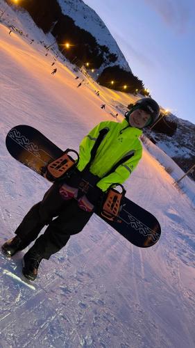 a woman is holding a snowboard in the snow at Sandersstua 2, luxury family apartment with private whirlpool in Stamsund in Vestvågøya