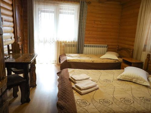 a bedroom with two beds and a desk and a window at Greku Hotel in Bukovel
