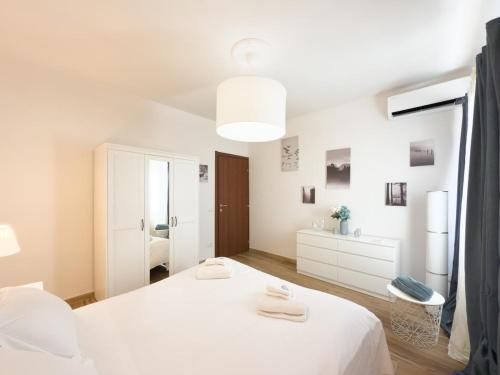 Un dormitorio blanco con una cama y un espejo. en Da Pinuccio, en Pisa
