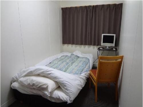 a small bedroom with a bed and a desk with a computer monitor at Eco Hotel Nagoya in Nagoya