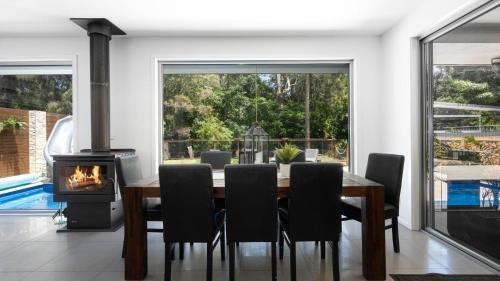 a dining room with a table and a fireplace at Marine Adventures in Callala Bay