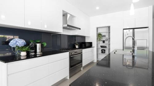 a kitchen with white cabinets and black counter tops at Marine Adventures in Callala Bay