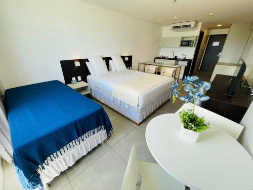 a bedroom with two beds and a table and a kitchen at Ritz Paradise Beira Mar no Hotel Ritz Suítes in Maceió