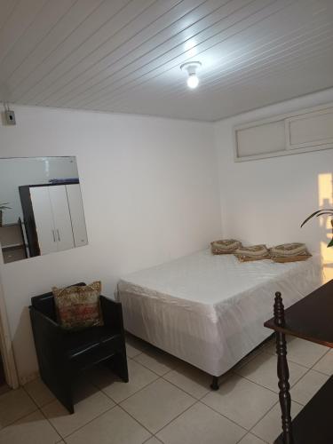 a bedroom with a bed and a chair and a mirror at Casa de verão in Capão da Canoa