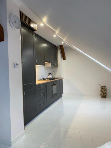 a kitchen with black cabinets and a clock on the wall at Apartament Woda i Zieleń in Borne Sulinowo