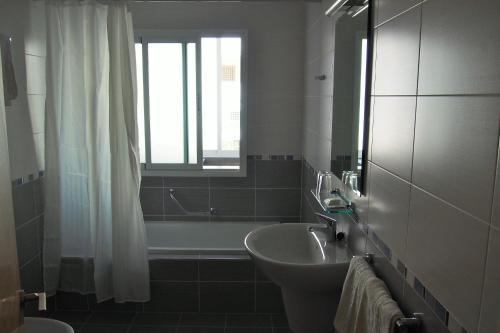 baño con lavabo y bañera con ventana en Hostal El Trovador, en Altea