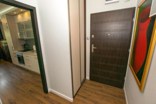 a bathroom with a brown door and a kitchen at Apartament Lena in Suwałki