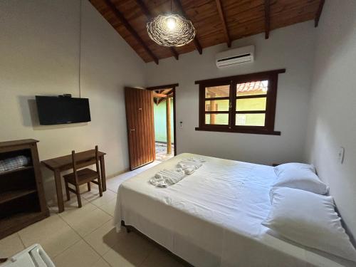 een slaapkamer met een wit bed en een televisie bij Eco Pousada Villa Verde in Bonito