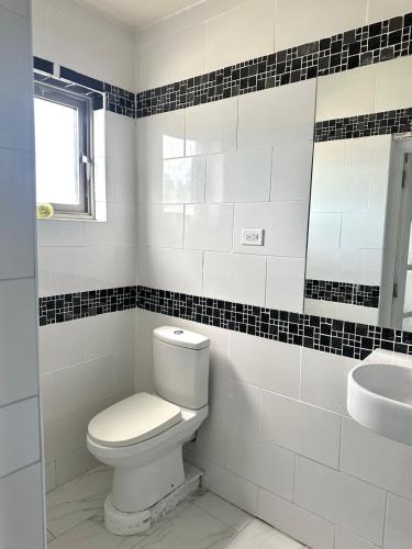 a white bathroom with a toilet and a sink at ShkyBlue Suites in Christ Church
