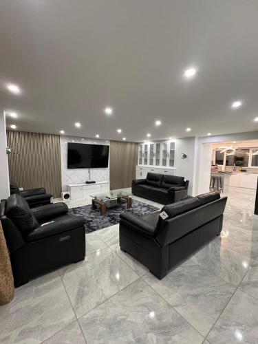 a living room with black furniture and a flat screen tv at Vancouver Place in Orpington