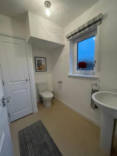 a bathroom with a toilet and a sink and a window at Inverness Retreat in Inverness