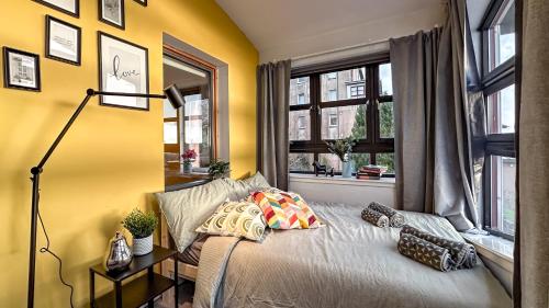 a bedroom with a bed with yellow walls and a window at Sunny day new flat with 5 beds in Clydebank