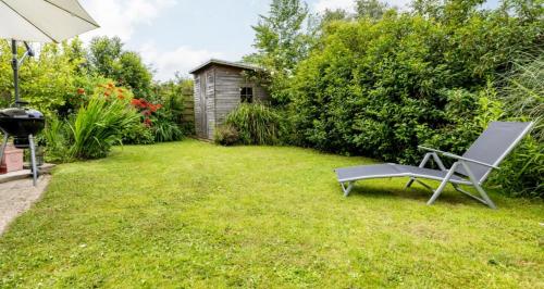 a chair sitting in the grass in a yard at VT wonen stijl vakantiebungalow nabij zee, strand, bos en duinen voor 6 personen in Warmenhuizen