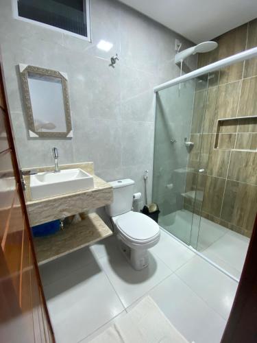 a bathroom with a toilet and a sink and a shower at Suítes Central Casal in Maragogi