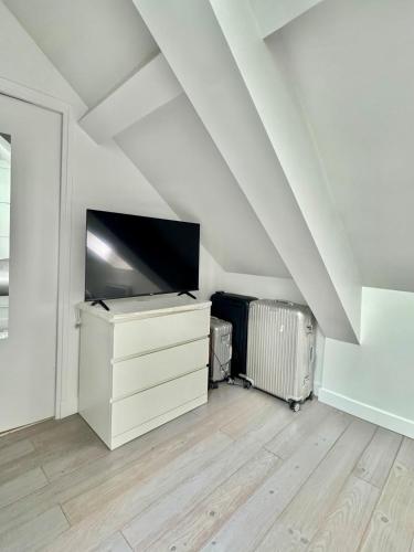 - un salon mansardé avec une télévision à écran plat dans l'établissement Charmant Parisien, à Paris