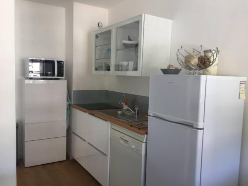 une cuisine avec des armoires blanches et un réfrigérateur blanc dans l'établissement Magnifique Studio cannes, à Cannes