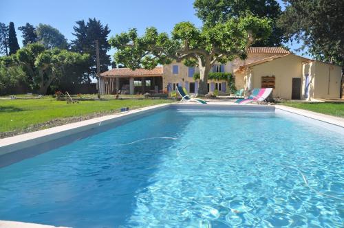 une piscine avec de l'eau bleue devant une maison dans l'établissement Manade Caillan, Mas Provençal Piscine, Pétanque, patio, à Maillane