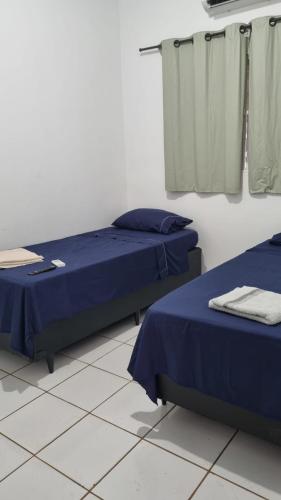two beds in a room with blue sheets at Turys Hotel Pousada in Chapadão do Sul