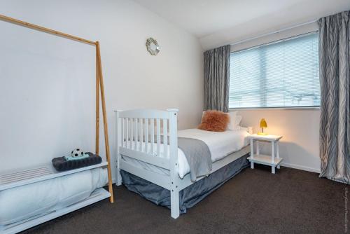 a bedroom with a white crib and a window at Urban Oasis Central Christchurch - parking in Christchurch