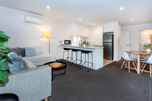 a living room with a couch and a kitchen at Urban Oasis Central Christchurch - parking in Christchurch