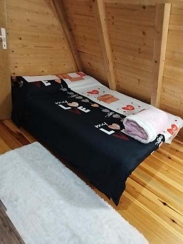 a bed with a black comforter and towels on it at Dedin Konak in Mokra Gora