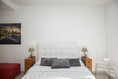 una camera da letto con un letto bianco e due comodini di Apartamento Riu Fluvià Girona a Girona
