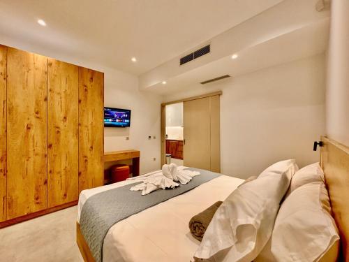 a bedroom with a bed with white sheets and a tv at ANESSIS Villas and Suites in Kalamaki Heraklion