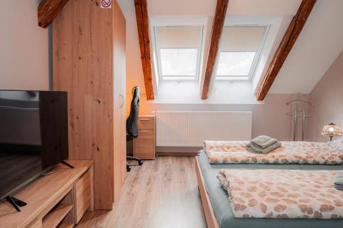 a bedroom with two beds and a tv and two windows at Apatmán Fellini House in Trenčín