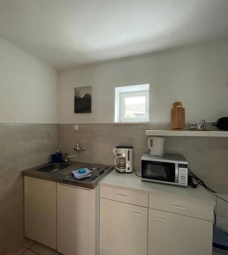 a small kitchen with a microwave and a sink at Gemütliche Wohnung Landlust in See-Nähe in Tauche