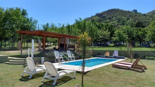 a swimming pool with chairs and a gazebo at Cabañas Casa Clara in Santa Rosa de Calamuchita