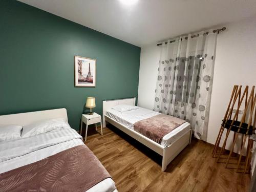 a bedroom with two beds and a green wall at Superbe 57 appartement in Hayange