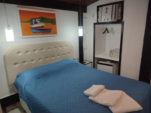 a bedroom with a blue bed with two towels on it at Pousada L'étage in Búzios