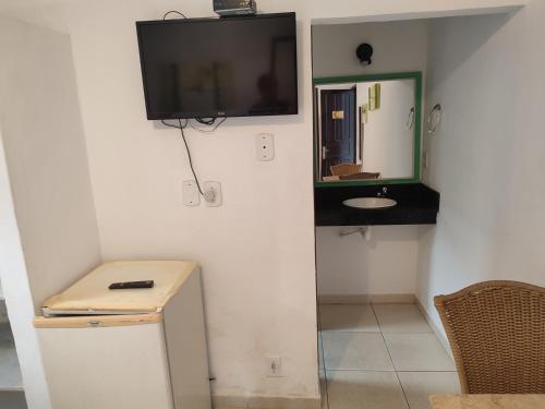 a bathroom with a tv on the wall and a sink at Pousada L'étage in Búzios