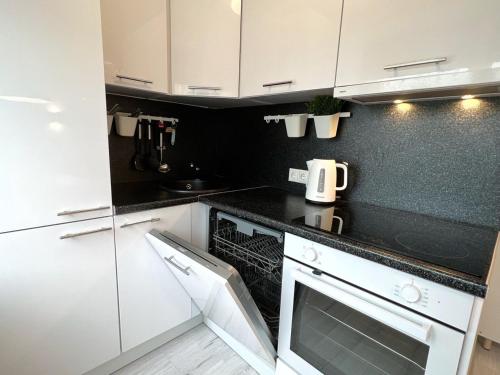 a kitchen with white cabinets and black counter tops at City Center Apartment in Narva