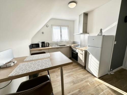 une cuisine avec une table et un réfrigérateur blanc dans l'établissement La Croix de Kerbigot - Guidel plage, à Guidel-Plage